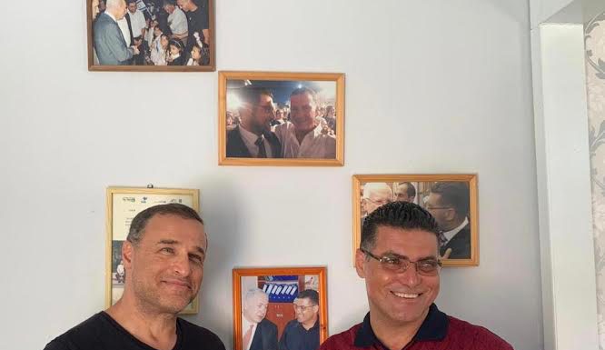 נאיל זועבי עם ליאור אקרמן על רקע קיר ראשי הממשלות והנשיאים שביקרו בביתו של נאיל
