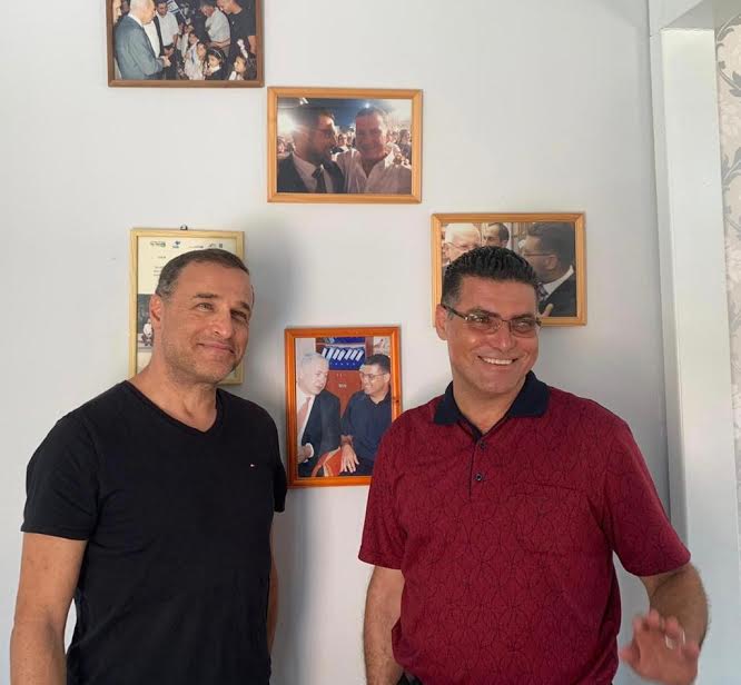 נאיל זועבי עם ליאור אקרמן על רקע קיר ראשי הממשלות והנשיאים שביקרו בביתו של נאיל