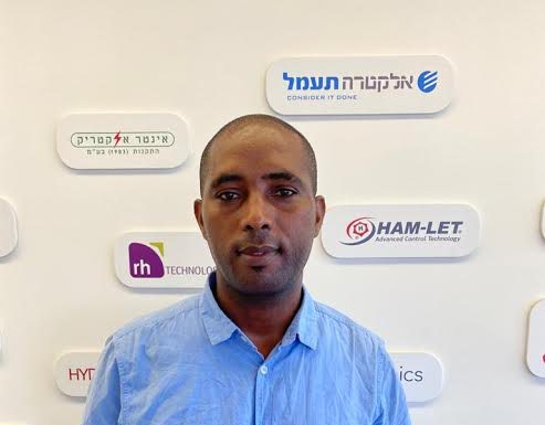 טרקו איינאו על רקע קיר התעשייה במכללה הטכנולוגית נוף הגליל.